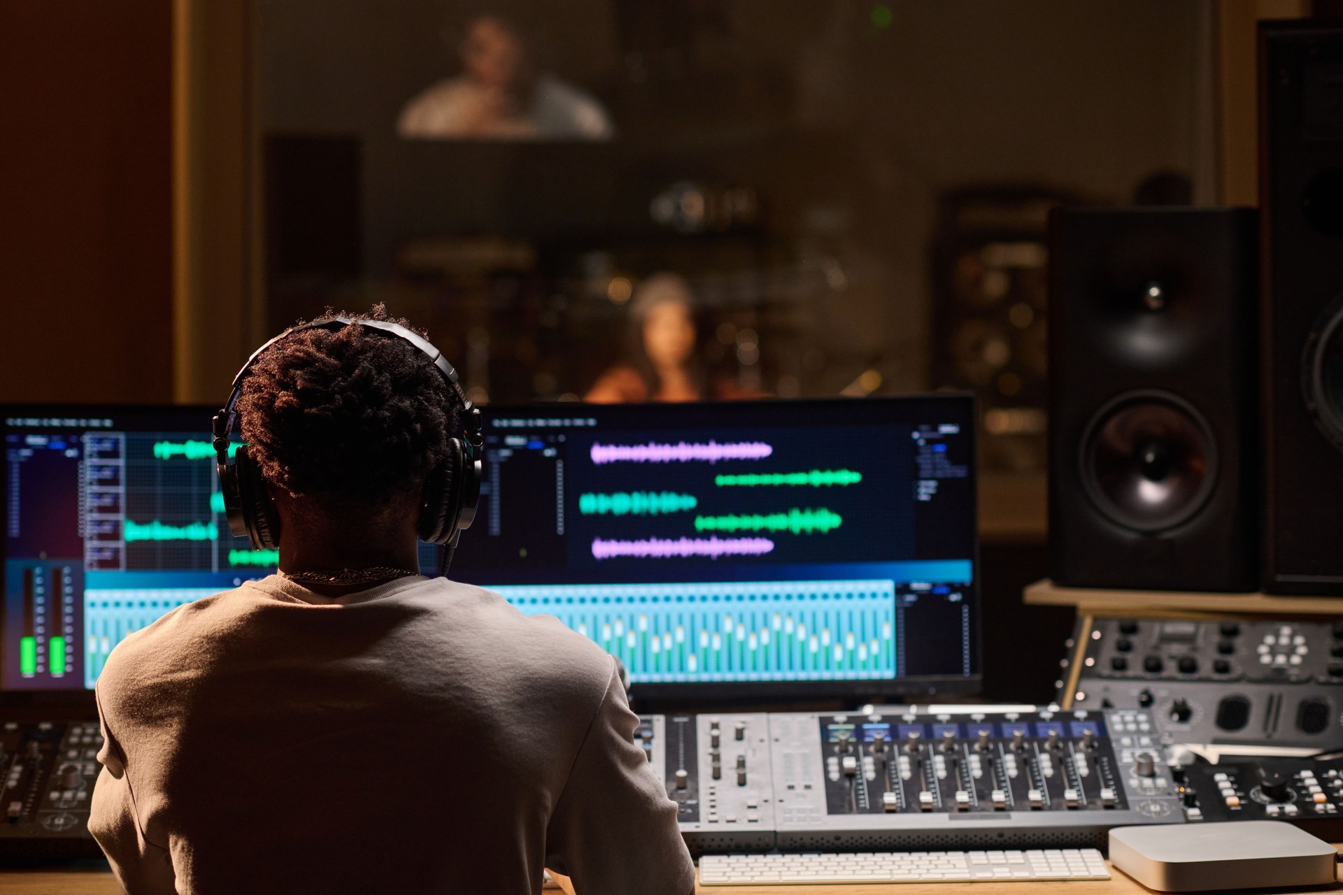 Young Adult Black Man Wearing Headphones Monitoring Audio Levels in Studio